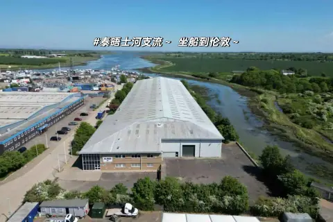 Aerial view of a long warehouse roof beside a road and waterway