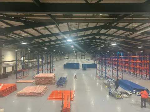 Warehouse interior with shelving components laid out on the floor